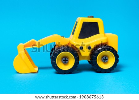 Toy yellow excavator on a blue background. Construction machinery car for digging for toy store and children.