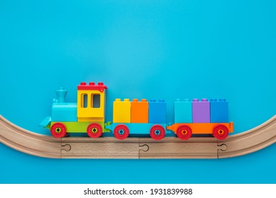 Toys background with copy space. Kids toy train with two carriages on wooden railway on blue background with copy space for text.