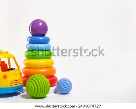 Toys for kids and play time. Pyramid with colored rings and purple ball on top, bright baby car isolated on white background. Copy space for text. 