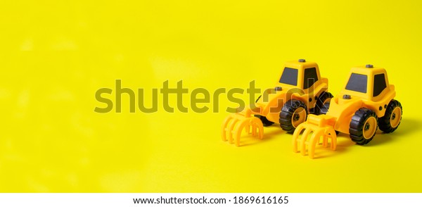Toys typewriter tractors on a yellow\
background. A banner with a place for text for a toy store. Bright\
background for the\
inscription.