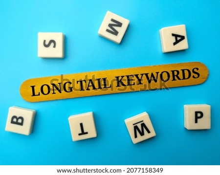 Toys word and colored ice cream stick with text LONG TAIL KEYWORDS on blue background.