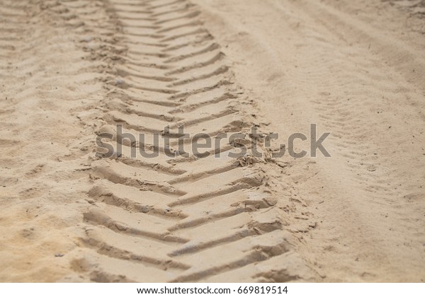 A trace on\
a sand of big wheel truck or\
tractor.