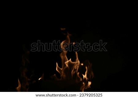Traces of bright golden orange flames against black background with copy space