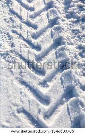 Traces of a car on white snow in winter.