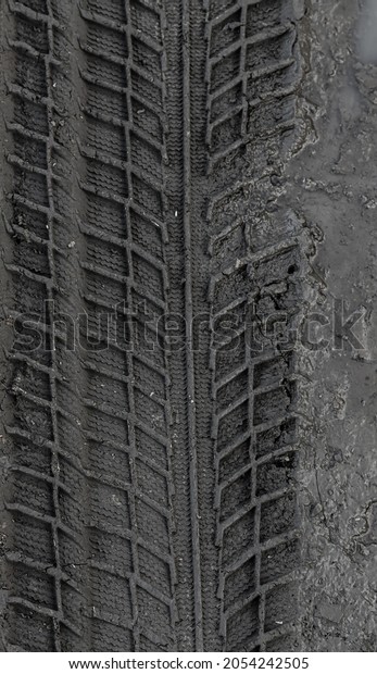 Traces\
of car tire tread in the ground. Pattern. Dark abstract background.\
Imprint of wheels. Textured soil. Drawing\
tires.