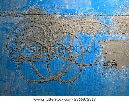 Traces of concentric shape like the Olympic rings and splashes of plaster mortar on a concrete wall prepared with a blue primer for covering with plaster on the construction of a residential building