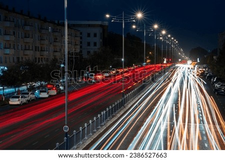 Traces of headlights of moving cars on the highway and street lights in the city at night. Blurred car movement.