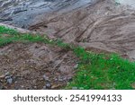 Traces of mud flows of earth washed away from green areas of park to the surface of asphalt, in the process of sudden flooding with huge amount of water due to a downpour or burst water pipe.