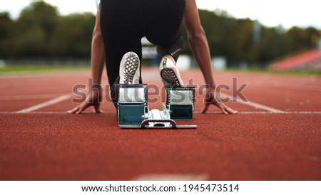 Track and Field Athlete being ready in the blocks alone with no competition, sprinter, empty lanes, lonely, training, practise, spikes