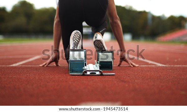 Track and Field Athlete being ready in the blocks\
alone with no competition, sprinter, empty lanes, lonely, training,\
practise, spikes