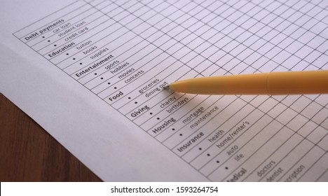 Tracking Of Household Spending. List Of Categories Of Family Or Personal Expenses On Paper: Mortgage, Rent, Utilities, Insurance And Debt Payments, Saving, Food, Clothing And Travel