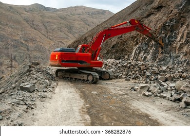 Tracklaying excavator with hydraulic hammer on the mountain road building spot