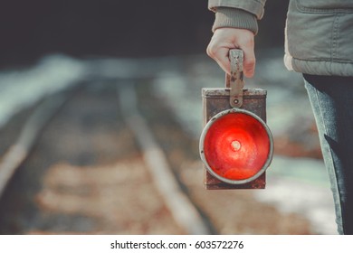 A trackman on the railway signals a red lantern