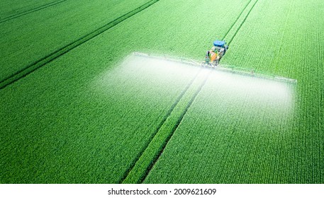 The tractor applies herbicides, pesticides or fertilizers to the green field. - Shutterstock ID 2009621609