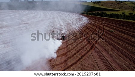 Tractor applying limestone to the soil to correct acidity