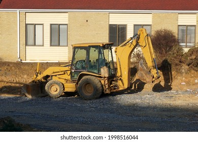 A Tractor Backhoe Sits In The Afternoon Sunshine Ready For Its Next Day's Job