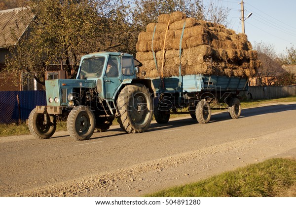 Tractor carrying  the load\
of hay bales. Agricultural scene in outback countryside. Rural\
landscape.