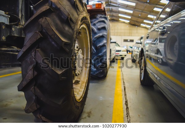 Tractor and\
cars parked in the garage for\
repair.