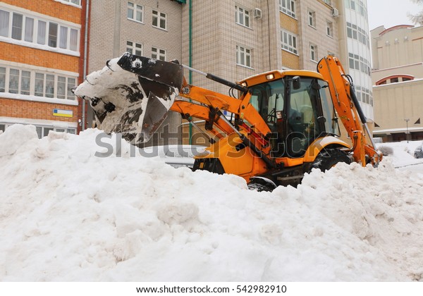 Tractor clean the\
yard from snow in the\
city.
