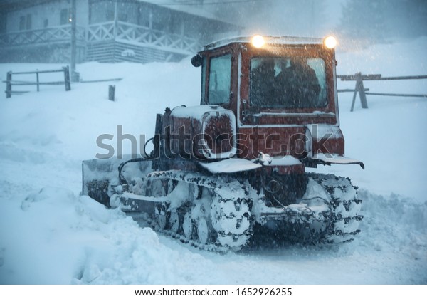 Tractor\
cleaning road in snowstorm. Winter\
season