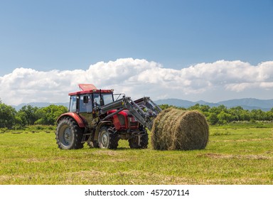 Tractor Collecting Hay Bales In The Fields