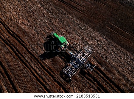 Tractor with cultivator plowing field. Tractor disk harrow on ploughing a soil. Planting in farmland. Sowing seed on plowed field. Seeding in agriculture. Farm Machinery for cultivating. Tractor plow.