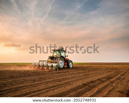 Tractor drilling seeding crops at farm field. Agricultural activity.