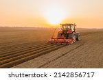 Tractor drives across large field making special beds for sowing seeds into purified soil. Agricultural vehicle works at sunset in countryside