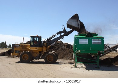 A Tractor Dumps A Pile Of Mulch Into A Mulching Machine