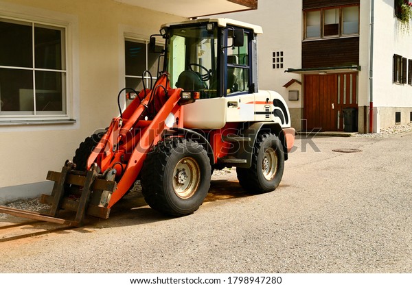 Tractor with\
equipment is in the farm\
yard.