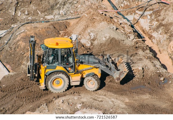 Tractor excavator with bucket rides\
running through mud lands setting, view from the\
height