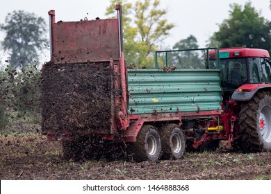 Tractor fertilizing field by spreading natural manure on soil