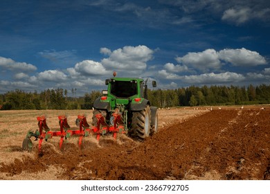 a tractor with a field and dozens of storks walking next to it - Shutterstock ID 2366792705