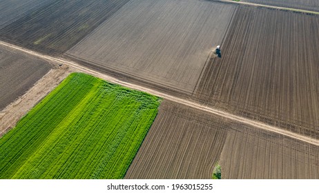 Tractor in field on a farm, aerial view. Top view of agricultural industrial tractor plows soil field for sowing , aerial shot from drone. Land cultivation, spring farming concept - Powered by Shutterstock