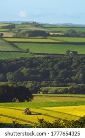 A Tractor In A Field Surrounded By Agriculture And Trees In Devon (UK)