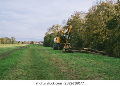 Tractor is in a field with trees in the background. The tractor is pulling logs
