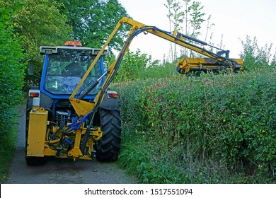 Tractor With Flail Cutting A Hedge In A Narrow Cotswolds Lane In Autumn, Gloucestershire, UK