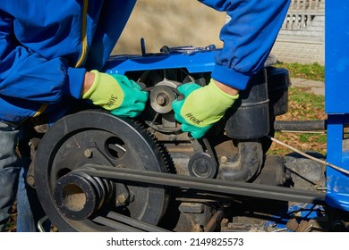 Tractor Generator Repair,a Man Replaces A Worn Cracked Generator Belt On A Two-wheeled Tractor