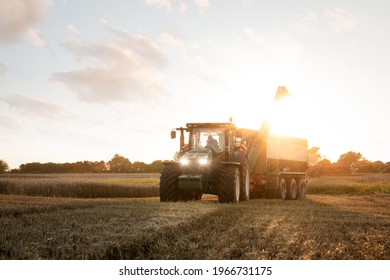 Tractor With A Grain Cart On A Field At Dusk