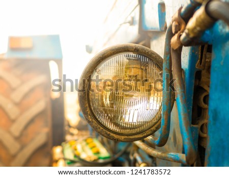 Tractor lights. Close up of old and dirty tractor headlight with clipping path ,circle sealed beam headlight for preparing land with seedbed cultivator at night. Car care concepts. - Selective focus.