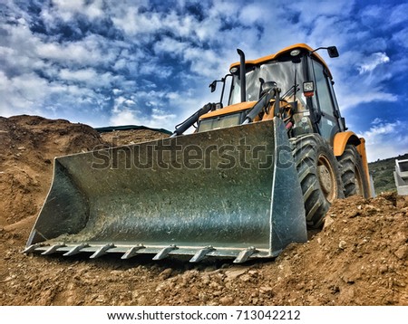 Tractor loader backhoe digger loader on a construction site with blue sky and dramatic clouds