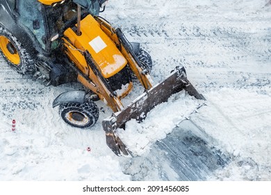 Tractor loader machine uploading dirty snow into dump truck. Cleaning city street, removing snow and ice after heavy snowfalls and blizzard. Snowplow outdoors clean pavement sidewalk road driveway - Powered by Shutterstock