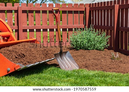 Tractor loader with wood chips or mulch and flowerbed. Lawncare, gardening and backyard landscaping concept