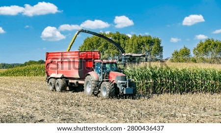 Tractor with a loading trailer and a corn chopper harvesting in a field - 4081