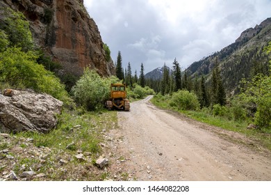 Tractor on a mountain road among the mountains and coniferous forests. Kyrgyzstan. Naryn Region