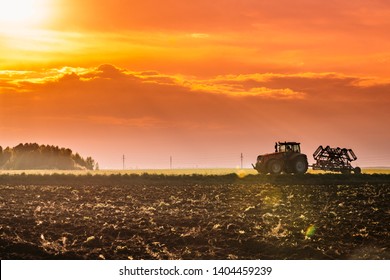 Tractor On Road In Spring Season. Beginning Of Agricultural Spring Season. Cultivator Pulled By A Tractor In Countryside Rural Field Landscape Under Sunny Spring Sunset Sunrise Sky. - Shutterstock ID 1404459239