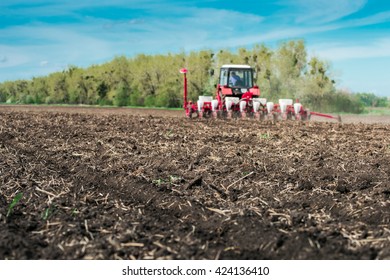 Tractor With Planter In The Field On A Sunny Day