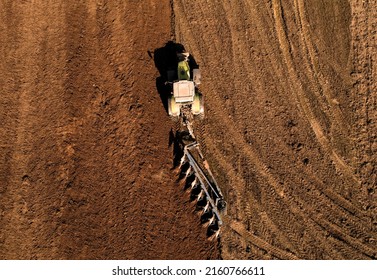 Tractor plowing field. Tractor plow soil cultivating. Cultivated land and soil tillage. Agricultural tractor on farm field cultivation. Tractor disk harrow plowing farm field. Agronomy and agrarian.
				