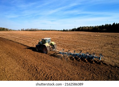 Tractor plowing field. Tractor plow soil cultivating. Cultivated land and soil tillage. Agricultural tractor on farm field cultivation. Tractor disk harrow plowing farm field. Agronomy and agrarian.

