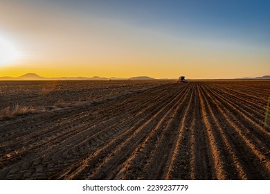A tractor plowing his field and a field in a sunset view